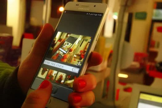 Close-up of a person's hand using a smartphone photography app indoors.