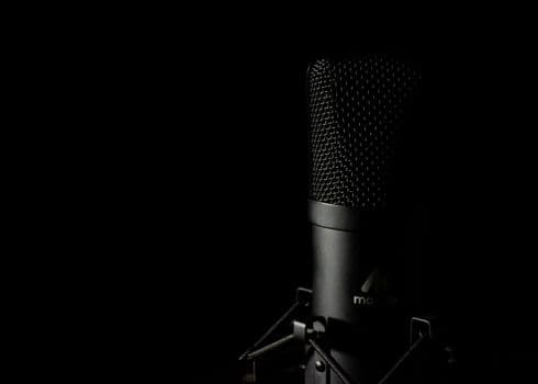 Detailed close-up of a studio microphone with a dark background, ideal for audio production themes.