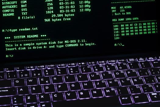 A classic MS-DOS terminal screen displayed on a laptop keyboard with vivid illumination.