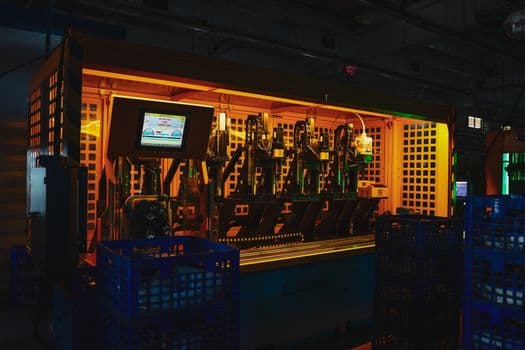 A complex piece of machinery in a dark industrial setting with vibrant lighting.