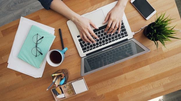 Aerial view of a contemporary desk setup with a laptop, coffee, and accessories, emphasizing productivity.