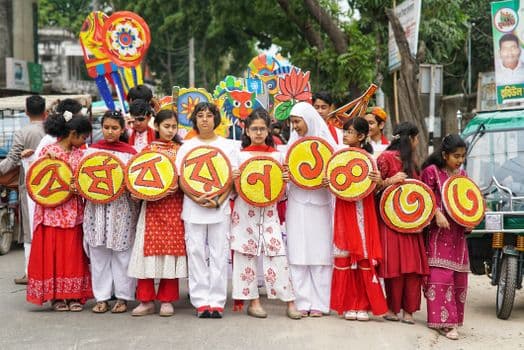 Young people celebrate the Boishakhi Festival in vibrant traditional outfits, holding decorative banners in Dinajpur, Bangladesh.