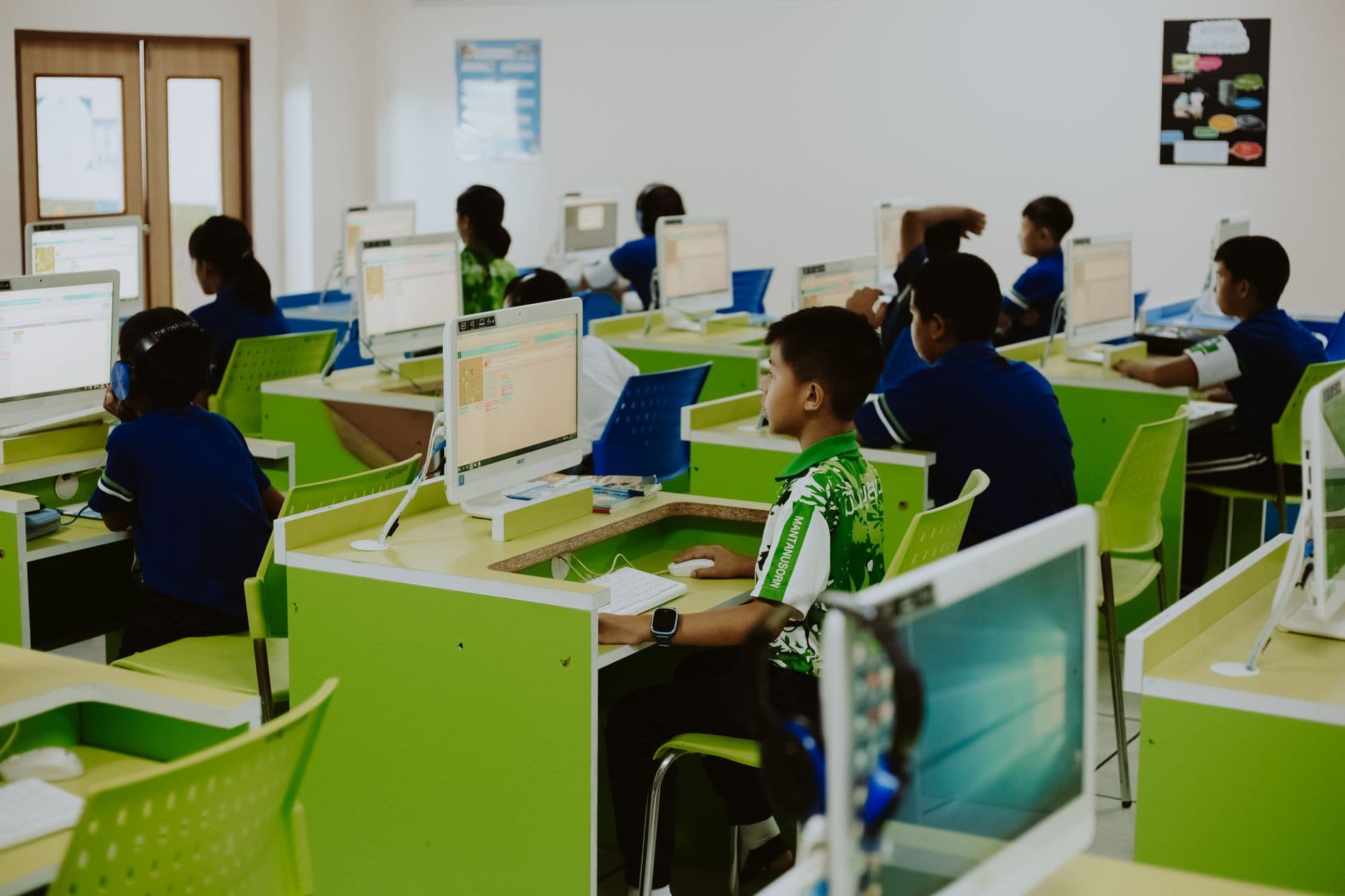 Children engaged in educational activities in a modern computer lab setting.