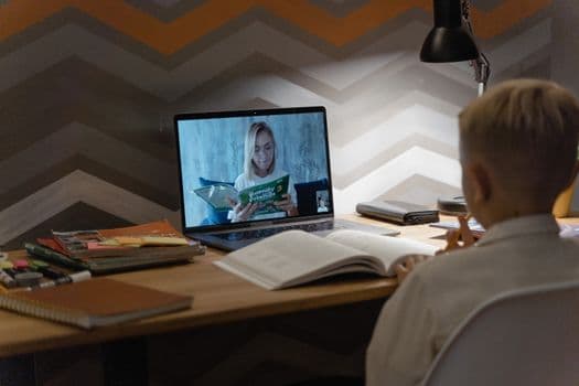 A child participates in an engaging online learning session via video chat on a laptop.