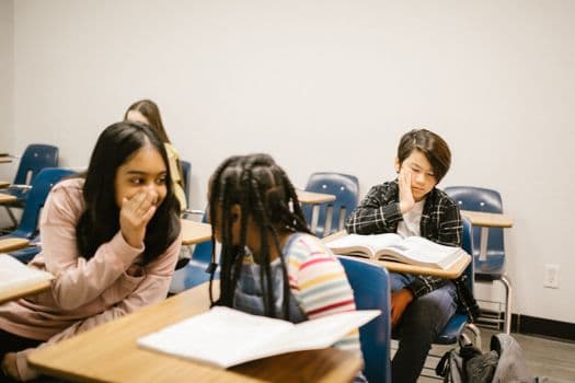Students talking and studying in a school classroom, highlighting social interaction and education.