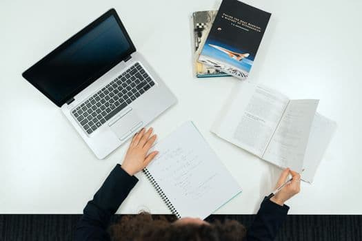Top view of a work desk with laptop, books, and notes showcasing productivity.
