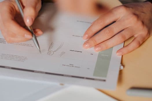 Close-up view of hands writing on a document, emphasizing note-taking and writing.