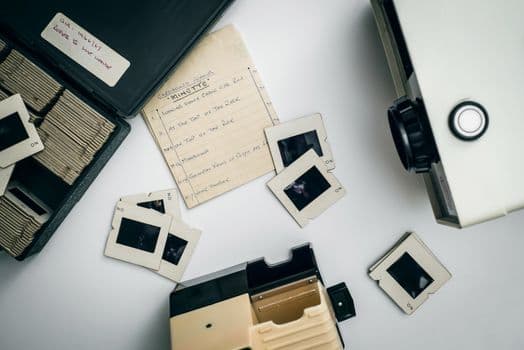 Flat lay of vintage slide projector and film slides, capturing nostalgia in photography.