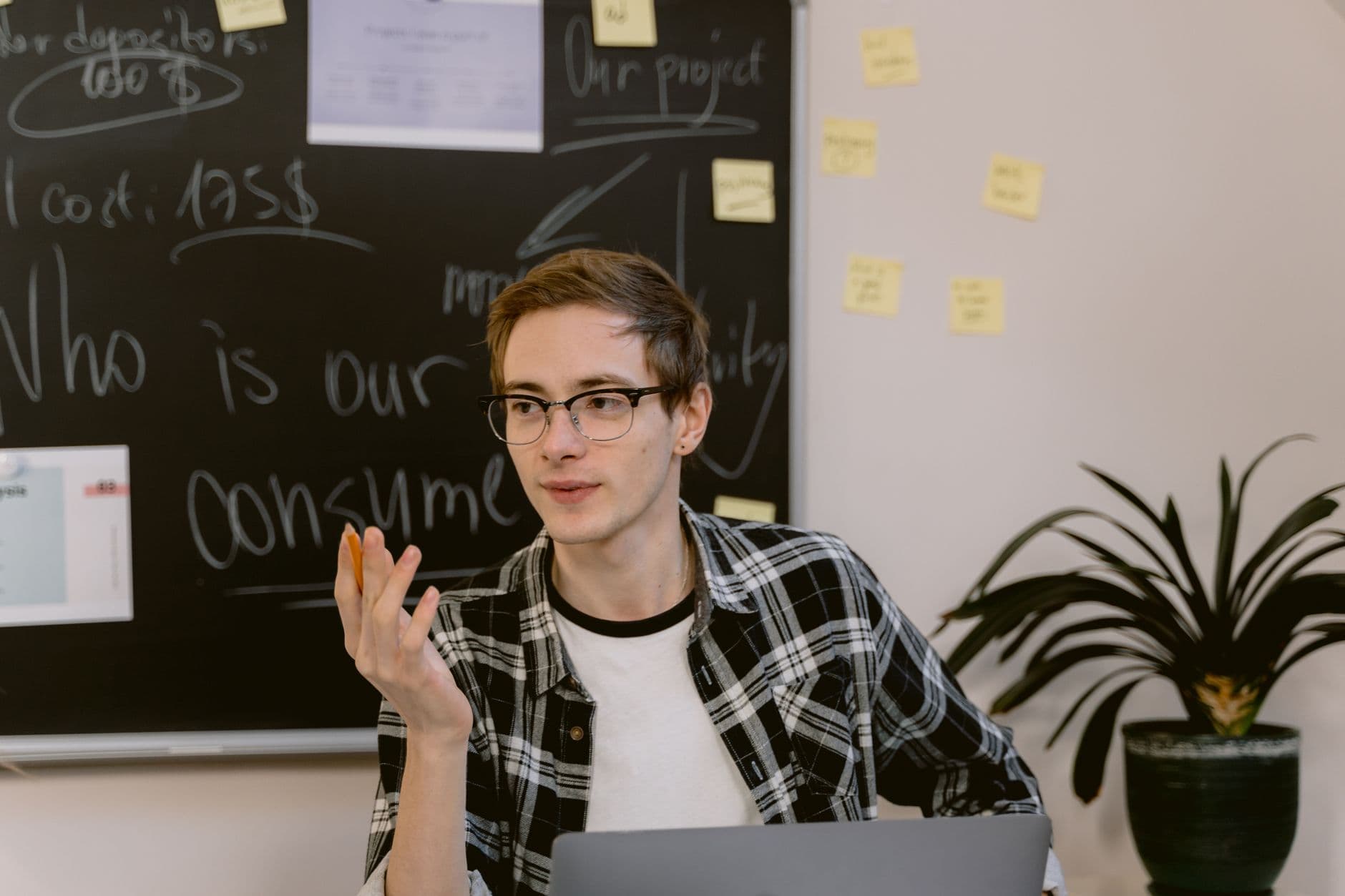 Young professional discussing ideas in a collaborative office setting with a chalkboard backdrop.