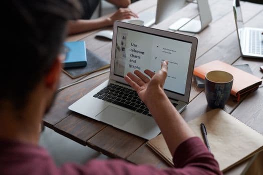A team collaborates around a laptop for project discussion in a modern office.